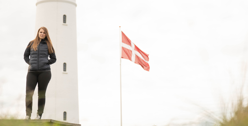Louise Frilev står foran Hirtshals Fyr. Dannebro i baggrunden.